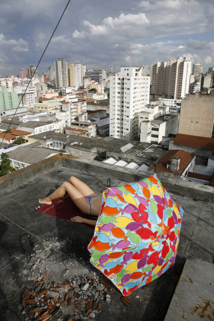 Big city beach - Woman sunbathing on the roof of building in downtown Sao Paulo.